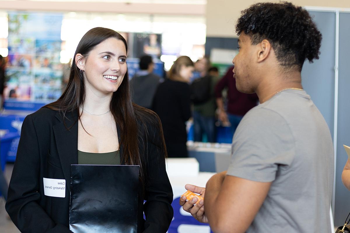 a person in professional clothes holding a folder and talking to someone